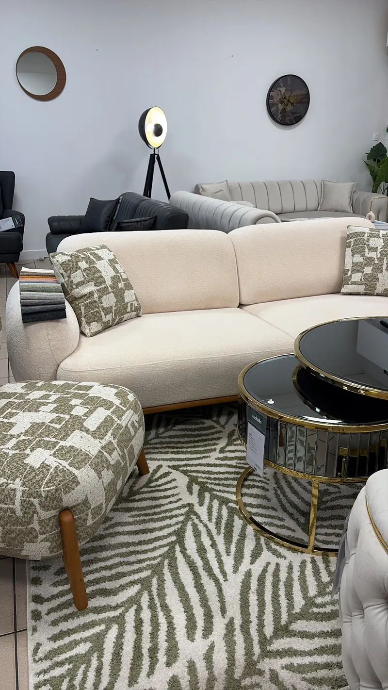 Un canapé crème sur un tapis à feuilles vertes, showroom du Mans